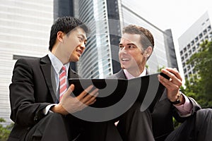 Two Businessmen Discussing Document Outside Office