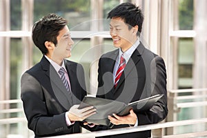 Two Businessmen Discussing Document Outside Office