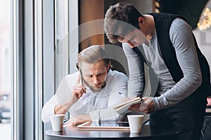 Two businessmen discussing work and using tablet