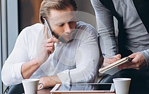 Two businessmen discussing work and using tablet