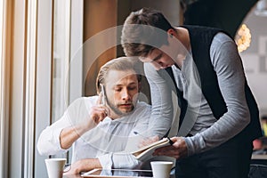 Two businessmen discussing work and using tablet