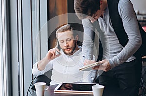 Two businessmen discussing work and using tablet