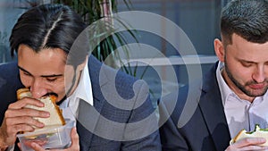 Two businessmen eating sandwich at lunch in office photo