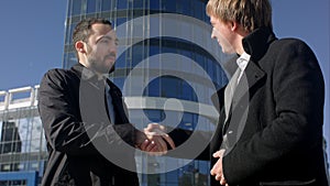 Two businessmen greeting each other by handshake outside