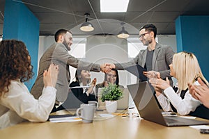 Two businessmen handshaking after striking grand deal in office