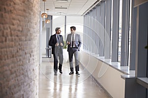 Two Businessmen Having Informal Meeting In Office Corridor