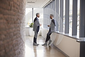 Two Businessmen Having Informal Meeting In Office Corridor
