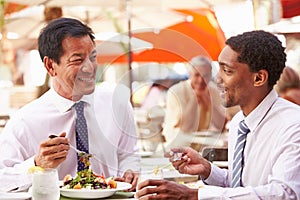 Two Businessmen Having Meeting In Outdoor Restaurant