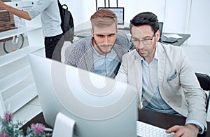 Two businessmen look at the computer monitor