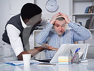 Two businessmen looking worriedly at laptop