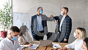 Two Businessmen In Masks Bumping Elbows During Corporate Meeting Indoor