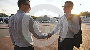 Two businessmen meeting at city street and greeting each other. Business handshake outdoor. Shaking of male arms outside