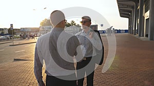 Two businessmen meeting at city street and greeting each other. Business handshake outdoor. Shaking of male arms outside