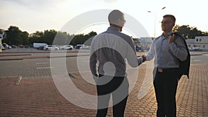 Two businessmen meeting at city street and greeting each other. Business handshake outdoor. Shaking of male arms outside