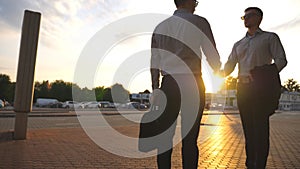 Two businessmen meeting at city street and greeting each other. Business handshake outdoor. Shaking of male arms outside