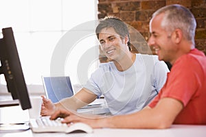 Two businessmen in office typing on computer