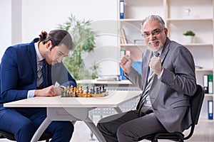 Two businessmen playing chess in the office