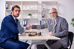 Two businessmen playing chess in the office