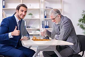 Two businessmen playing chess in the office