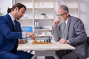 Two businessmen playing chess in the office