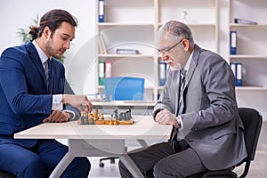 Two businessmen playing chess in the office