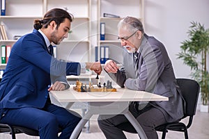 Two businessmen playing chess in the office