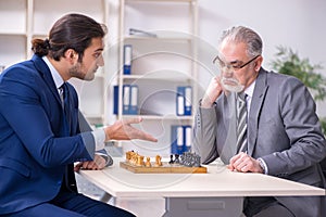 Two businessmen playing chess in the office
