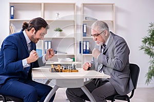 Two businessmen playing chess in the office