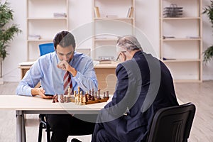 Two businessmen playing chess in the office