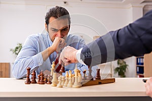 Two businessmen playing chess in the office