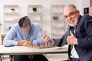 Two businessmen playing chess in the office