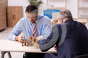 Two businessmen playing chess in the office