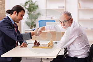 Two businessmen playing chess in the office