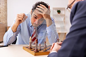 Two businessmen playing chess in the office