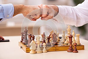 Two businessmen playing chess in the office