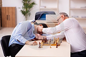 Two businessmen playing chess in the office