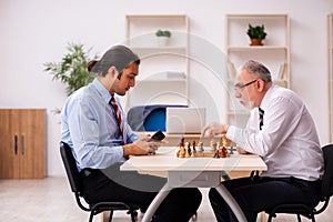 Two businessmen playing chess in the office