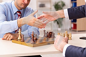 Two businessmen playing chess in the office