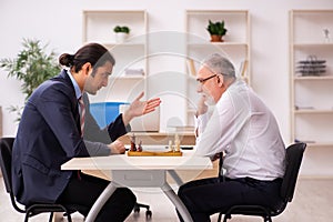 Two businessmen playing chess in the office