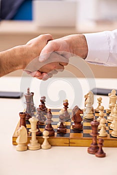 Two businessmen playing chess in the office