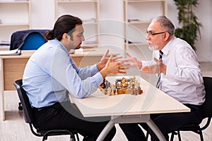 Two businessmen playing chess in the office