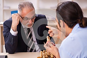 Two businessmen playing chess in the office