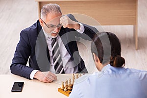 Two businessmen playing chess in the office