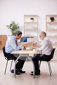 Two businessmen playing chess in the office