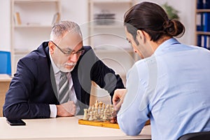 Two businessmen playing chess in the office