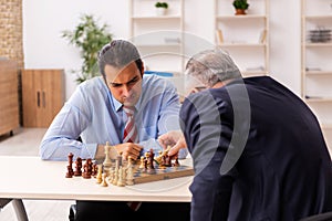 Two businessmen playing chess in the office