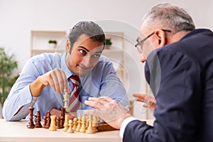 Two businessmen playing chess in the office