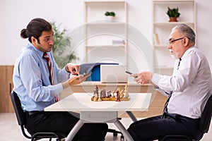 Two businessmen playing chess in the office