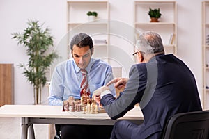 Two businessmen playing chess in the office