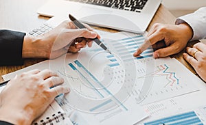 Two businessmen are pointing to the company sales graph paper and then analyzing together